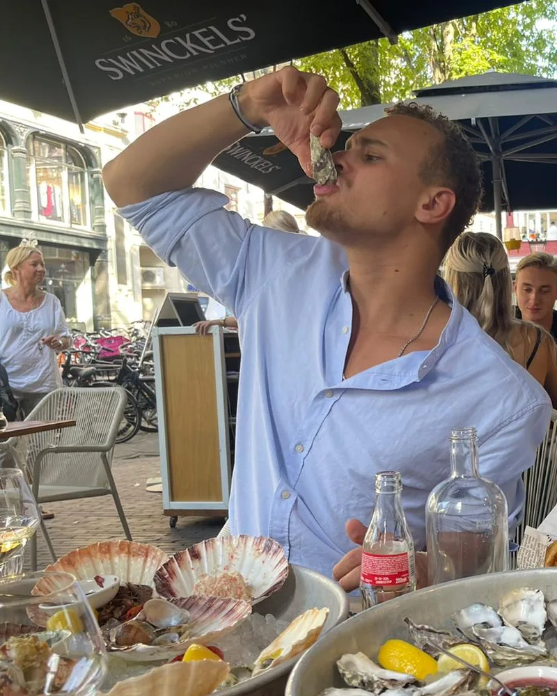 Nelson Archer eating an oyster on a terrace